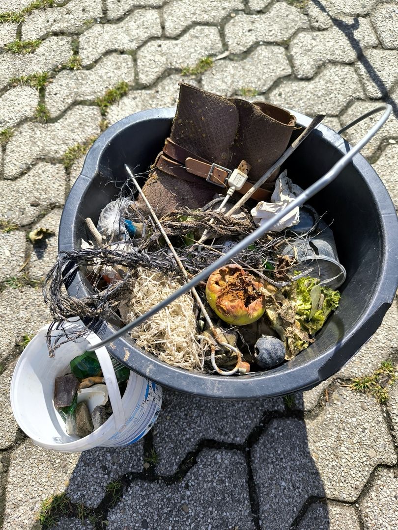 Ein Mülleimer voller Abfälle, darunter ein Schuh und verschiedene Gegenstände.