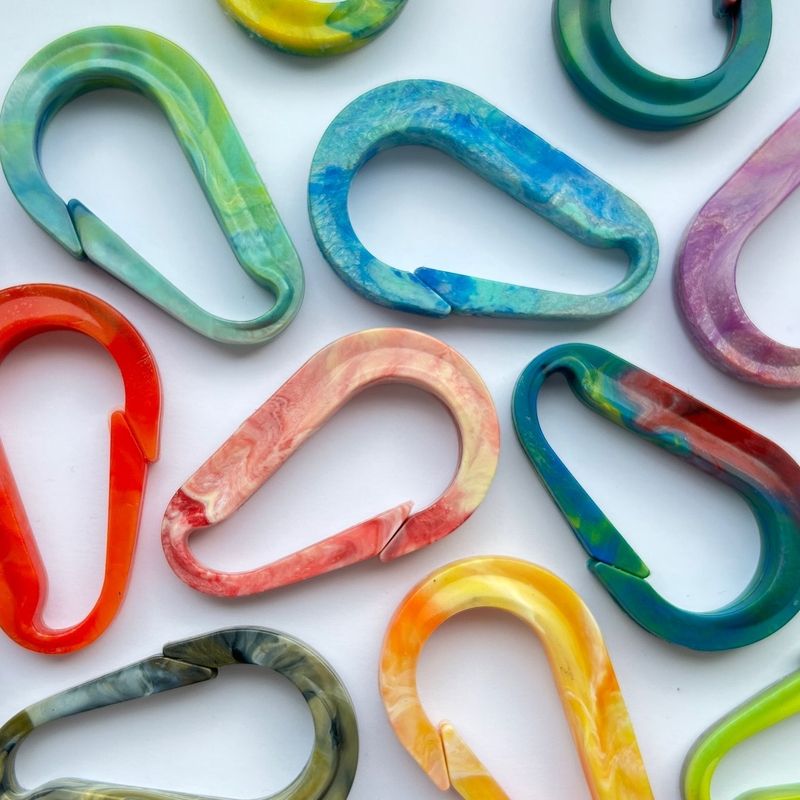 Bunte Karabinerhaken in verschiedenen Farben auf weißem Hintergrund.