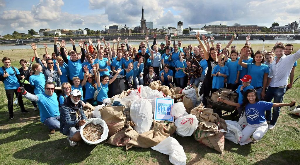Freiwillige bei der Rhein Cleanup-Aktion mit Müllsäcken.